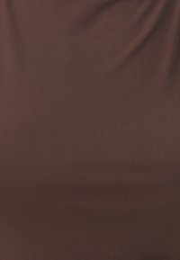 Brązowa tkanina o gładkiej fakturze, z drapowanym wzorem tworzącym miękkie fałdy. Brak widocznych wzorów i detali metalowych.