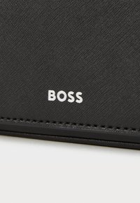 Black wallet with textured fabric, featuring white "BOSS" logo. Simple design with visible stitching and smooth edges.