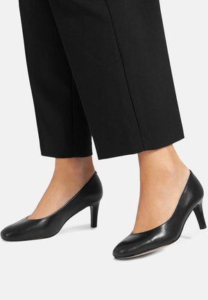 Zapatos de tacón alto de cuero negro con punta redondeada y acabado pulido. Tacón de altura media y diseño liso y elegante.