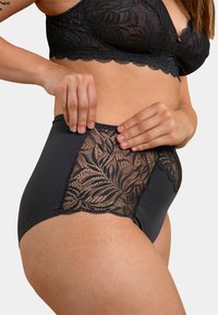 Culotte noire taille haute avec un panneau en dentelle transparente à motif floral sur les côtés, tissu lisse et ceinture élastique douce.