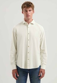 Helebeež pikkade varrukatega särk nööbiga kraega ja peene tekstuuriga, slim fit'i lõikega ja ühe rinnataskuga, sobitatuna teksadega.