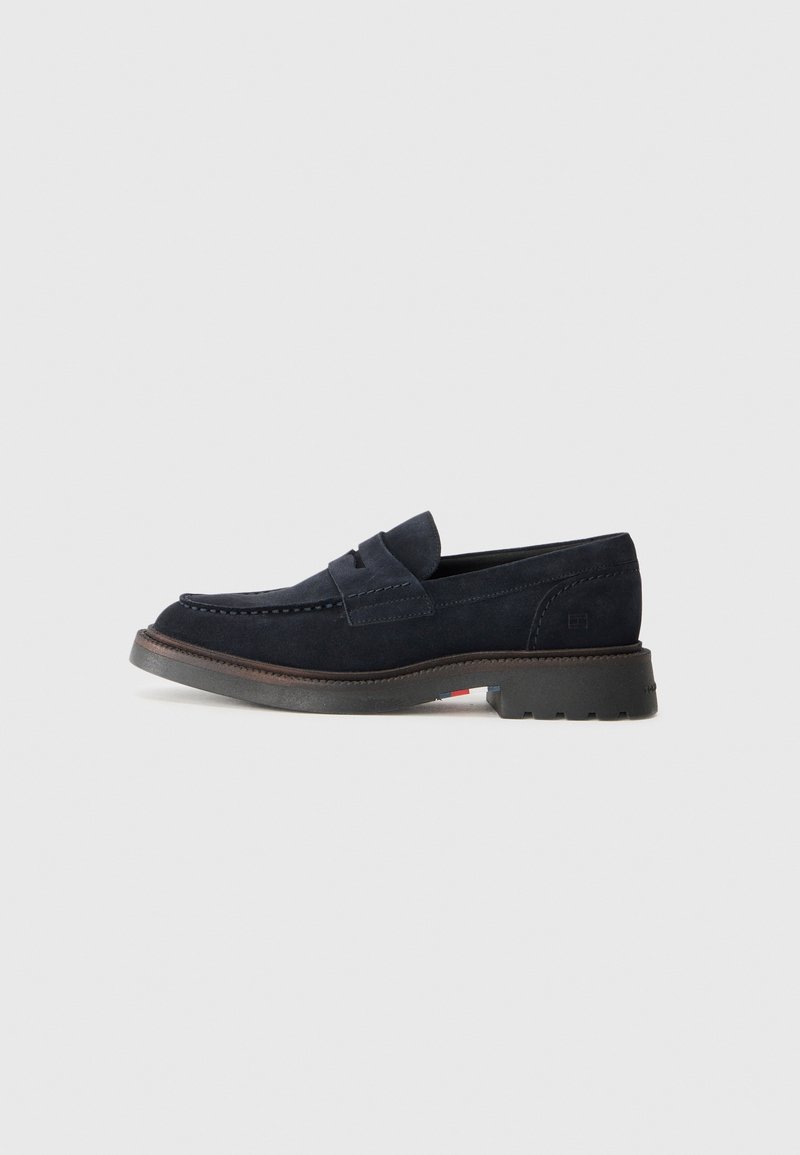 Mocassins en daim bleu marine avec un bout arrondi, une couture décorative et une semelle en caoutchouc légèrement surélevée. Matériau et design durables.