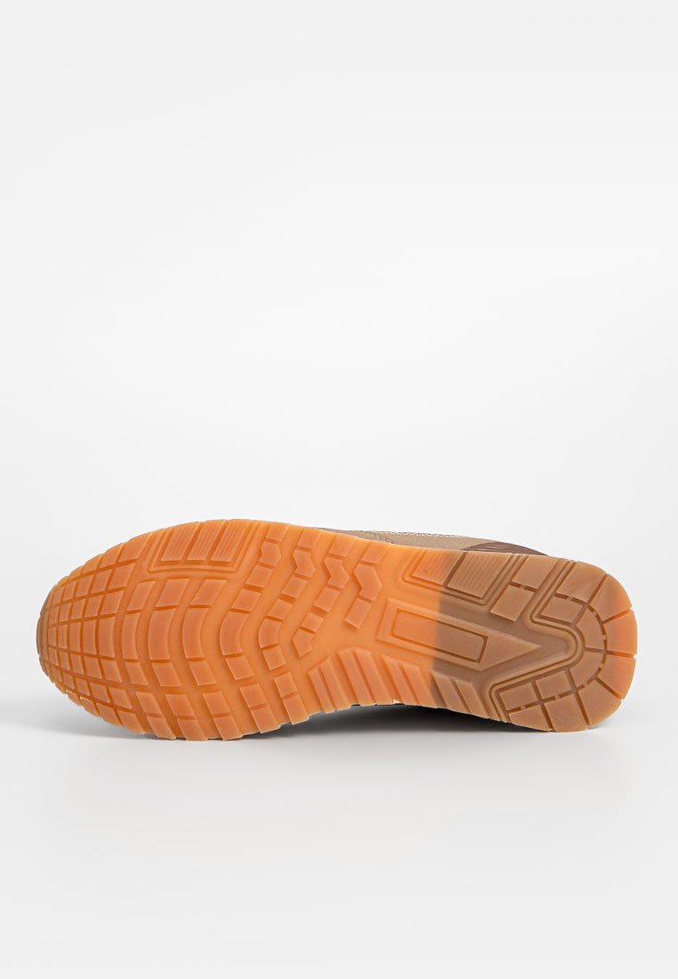 Zool van een schoen met een gestructureerd, patroonontwerp in oranje rubber, dat overgaat in een bruin materiaal aan de bovenrand.