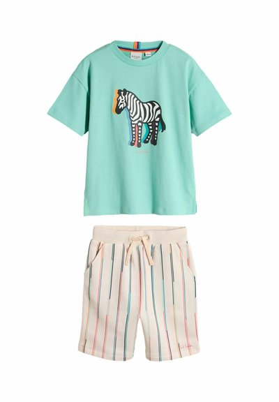 Mintgrøn kortærmet T-shirt med farverigt zebra-motiv, kombineret med cremefarvede shorts med lodrette flerfarvede striber og snøre i taljen.