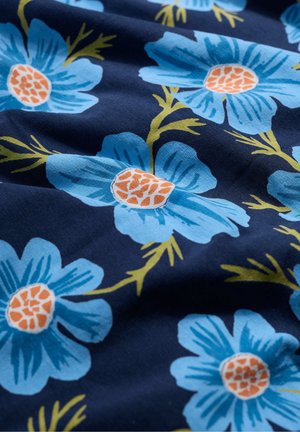 Tissu avec de grandes fleurs bleues à centres orange sur un fond marine foncé, agrémenté de feuilles vertes. Texture douce du tissu visible.
