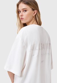 Biała, oversize'owa koszulka z krótkim rękawem, z haftowanym napisem "ALLSAINTS" w kolorze srebrnym na plecach. Wykonana z miękkiej, lekkiej bawełny. Okrągły dekolt.