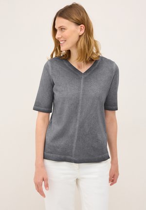 Grijze T-shirt met korte mouwen en V-hals, gemaakt van zachte stof, met een ontspannen pasvorm en subtiele textuur. Draagt met lichtgekleurde broek.
