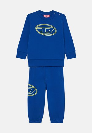 Blue sweat suit set with long-sleeve top and jogger pants. Features a large yellow and black logo on the front and gathered cuffs.