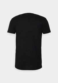 T-shirt noir à manches courtes présenté de dos sur un fond gris clair uni.