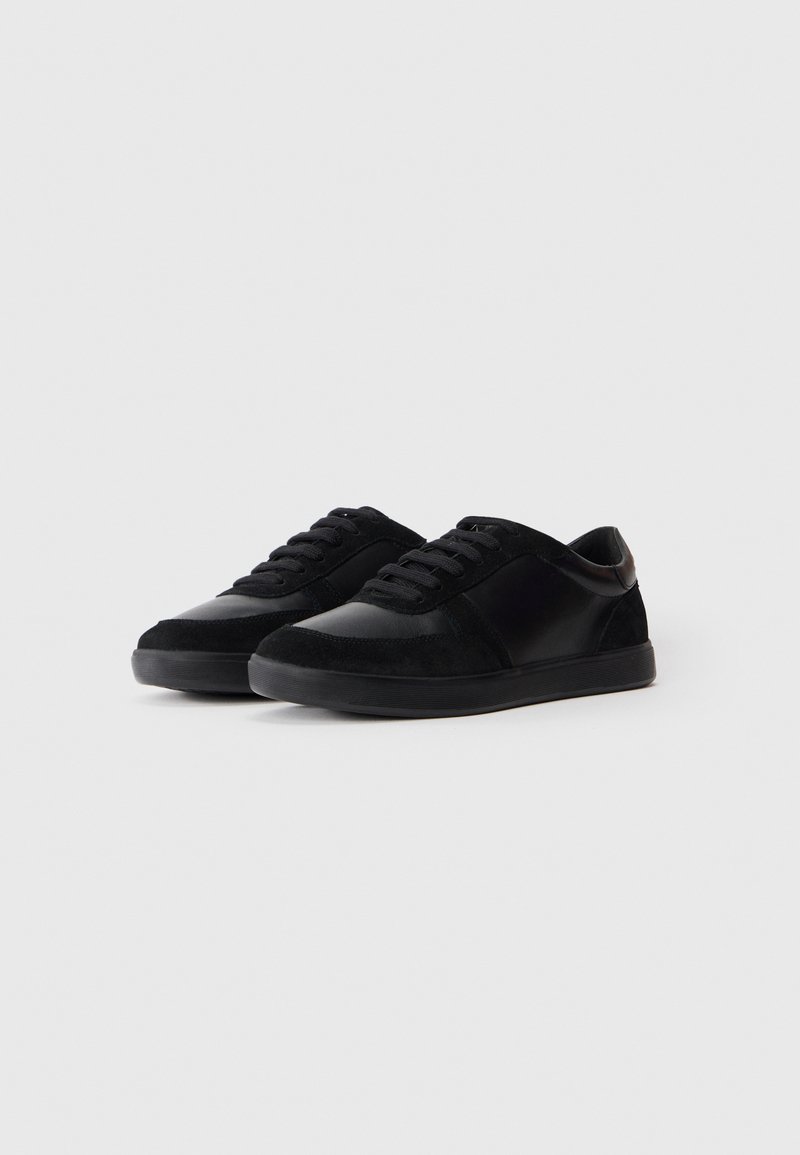 Zapatillas negras hechas de ante y cuero sintético, con puntera redonda, cierre de cordones en la parte delantera y suela de goma texturizada.
