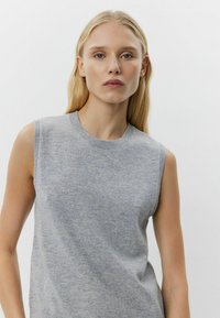 Pulover gri fără mâneci, cu guler rotund, realizat dintr-o țesătură moale, având o textură fină și detalii de design minime.