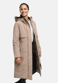 Parka beige longue avec capuche, fermeture éclair à l'avant et grandes poches. Elle possède une doublure matelassée et un extérieur lisse et résistant à l'eau.