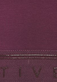 Deep purple fabric with ribbed texture, featuring a glossy, embossed logo. Seam details are visible at the bottom edge.