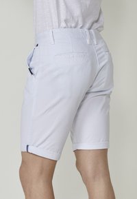 Svijetloplavi pamučni šorts s rolled cuffs, bočnim i stražnjim džepovima te suptilnim detaljima šivanja. Glatka tekstura, ležeran dizajn.