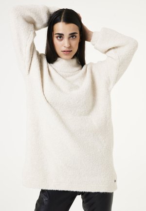 Cremfarbener, grob gestrickter Pullover mit hohem Kragen, überschnittenen Schultern und strukturiertem Finish. Leicht mit langen Ärmeln.