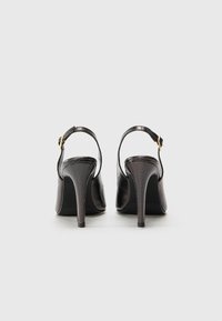 Sandali neri con tacco alto e finitura testurizzata, che presentano un design slingback e una fibbia in tono oro. Tacco a spillo alto e punta chiusa.