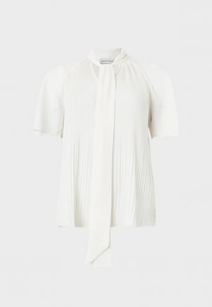 Valge lühikeste varrukatega pluus volditud eesosaga ja pikk kitsas lips ripub keskel all.