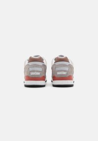 Šedii nubuk i mrežasti tenisice s bijelim i crvenim detaljima, s podstavljenim ovratnikom i "Saucony" logotipom na peti.