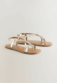 Metallic gouden sandalen met gevlochten banden, platte zool, open teenontwerp en een verstelbare gespsluiting. Textuuraccenten verbeteren het visuele detail.