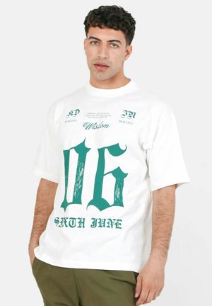 Hvid bomuld t-shirt med stort grønt print af tallet "06" og "SIXTH JUNE" med dekorativ tekst ovenfor. Korte ærmer, rund hals.