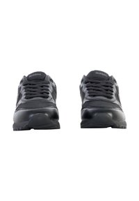 Chaussures de sport noires avec une tige en cuir et synthétique, une languette texturée, un laçage et une semelle en caoutchouc avec un motif de denture.