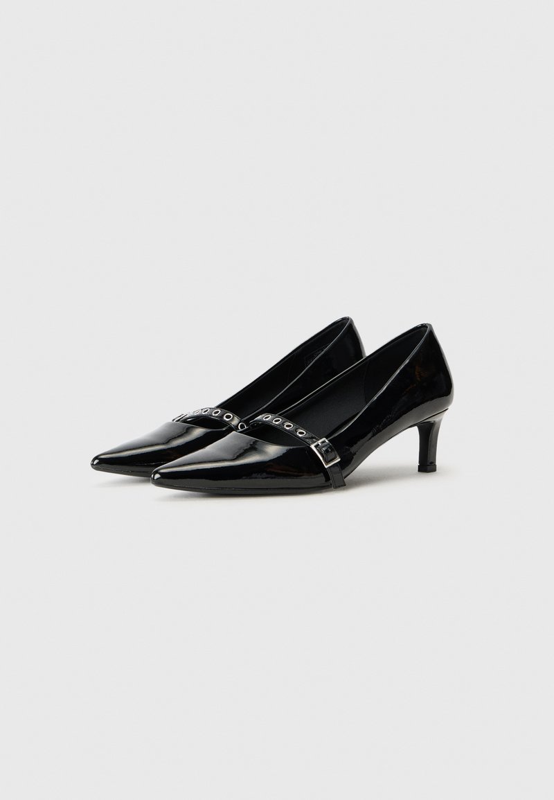 Zapatos de charol negro con puntera afilada, tacones pequeños y una correa decorativa que presenta recortes circulares y un detalle de hebilla.