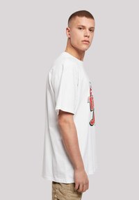 Hvid bomulds t-shirt med afslappet pasform, rund halsudskæring og korte ærmer. Har farverig grafisk print på forsiden.
