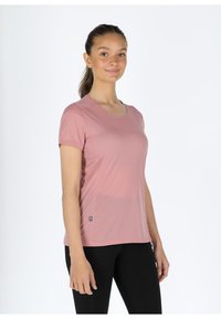 Short-sleeve, light pink athletic shirt with a round neckline, textured fabric, and subtle seam detailing. Small logo at the hem.