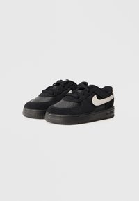 Sneakers neri bassi realizzati in suede e pelle, con una parte superiore testurizzata, lacci neri e un accento bianco del logo Nike.