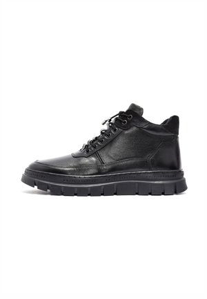 Zapatillas altas de cuero negro con superficie texturizada, cordones en la parte delantera y suela de goma gruesa. Presenta un sutil estampado en el borde de la suela.