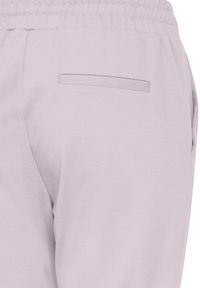 Ljuslila joggers med elastisk midja, slät textur och en enda bakficka. Tyget verkar mjukt och har en avslappnad design.