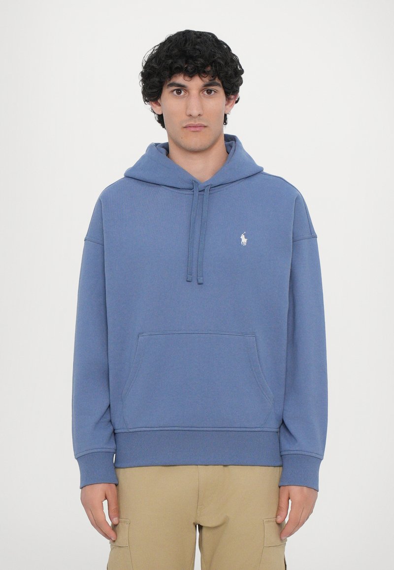 Blå sweatshirt med hætte lavet af bomuldsblandingsstof. Har en frontlomme, snøre i hætten og broderet logo på brystet.