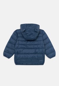 Veste matelassée bleu marine avec capuche comportant de petites oreilles décoratives, coutures horizontales et poignets élastiques ; fabriquée dans un matériau léger et brillant.