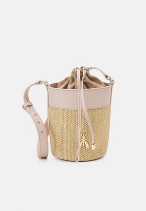 Kleine beige bucketbag met geweven structuur, verstelbare riem, trekkoordsluiting en gouden decoratieve bij-anhanger aan de voorkant.