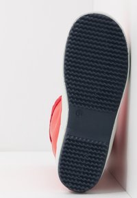 Kumisaappaan pohja, jossa on rakenteellinen tummansininen kuvio, punainen yläosa ja valkoinen reuna. Sivulla on kokoindikaattori '34' kohokuvioituna.