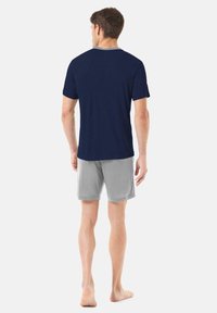Camiseta de color marino con cuello gris y pantalones cortos grises, ambos hechos de una tela suave, vistos desde atrás. Diseño simple sin patrones.