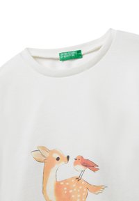 Felpa bianca in cotone con un'illustrazione di un cervo e un uccello. Il design include tonalità di arancione e marrone con macchie bianche.