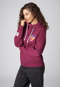 Bordeauxrode hoodie met een grafisch ontwerp aan de voorkant, met kleurrijke bloemmotieven. Heeft trekkoorden, geribde manchetten en een zijlabel.
