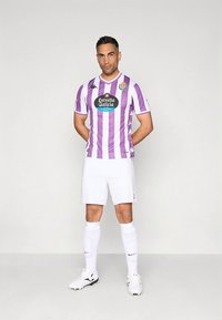 Balta futbola kreklam ar vertikālām violetām svītrām, apaļu apkakli un logotipu. Kombinēts ar baltiem šortiem un zeķēm, melni baltas kurpes.