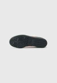 Black rubber sneaker sole with textured grip pattern, circular accent in the center, and a smooth finish along the edges.