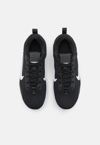 Pantofi sport negri cu un exterior texturat, swoosh-uri albe Nike, șireturi rotunde, accente negre și un tag pentru a facilita îmbrăcarea.
