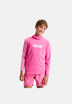 Junge lächelnd, trägt ein knallpinker Langarmshirt und passende Shorts mit weißem „SLAM“-Logo auf der Vorderseite des Shirts.