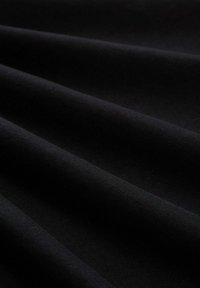 Tessuto nero con una texture liscia e una leggera lucentezza, caratterizzato da morbide pieghe e drappeggi, che mostra un colore uniforme senza motivi o decori.