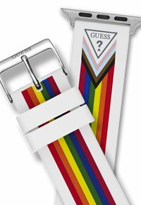 Biała silikonowa bransoleta z wielokolorowymi pionowymi paskami w kolorach czerwonym, żółtym, zielonym, niebieskim i brązowym. Metalowa klamra z wygrawerowanym napisem "GUESS".