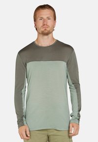 Langarmshirt in hellgrün und dunkelgrün, aus weichem Stoff. Verfügt über einen runden Halsausschnitt und ein kontrastierendes Paneeldesign auf der Brust.