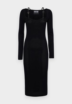 Mustapituinen pitkähihaisen mekko, jossa on tiukka siluetti, valmistettu teksturoidusta kankaasta, jossa on pieniä reikiä ja säädettävät olkaimet.