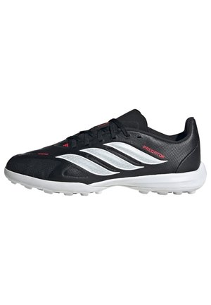 Chaussure de football Adidas Predator noire et blanche avec trois bandes blanches, fermeture à lacets et semelle texturée pour une meilleure traction.