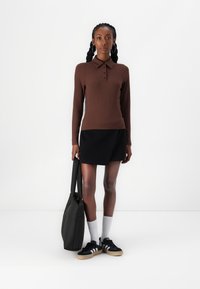 Brown ribbed long-sleeve polo shirt, black mini skirt, black sneakers with white accents, and a black tote bag. Smooth textures throughout.
