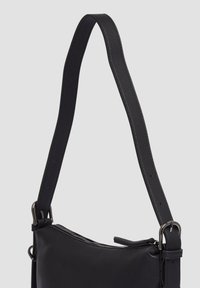Borsa a tracolla in pelle nera con finitura testurizzata, dotata di una tracolla sottile e chiusura con cerniera. Accentuata da metalli.
