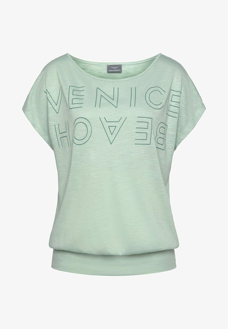 T-shirt vert menthe à manches courtes avec une coupe ample, présentant un texte en gras "VENICE BEACH" en vert foncé, un col rond et un tissu doux et texturé.